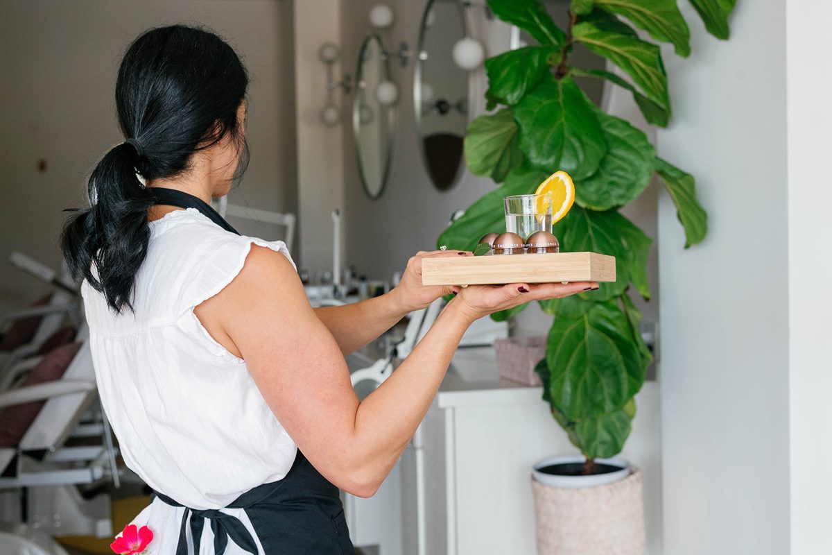 An esthetician carries a treatment tray through the studio