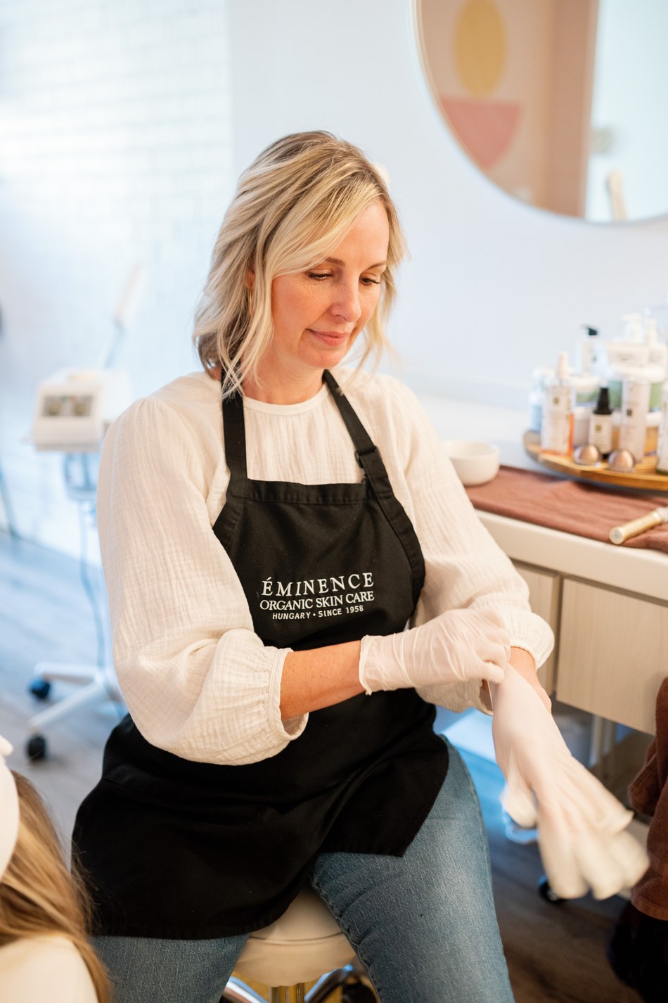 An esthetician in an Éminence apron prepares a treatment